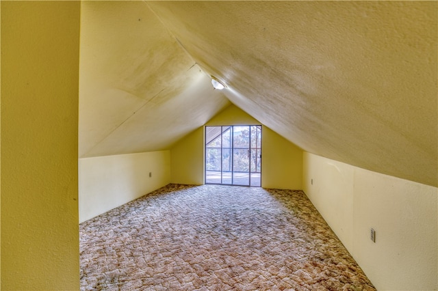 additional living space featuring vaulted ceiling, carpet flooring, and a textured ceiling