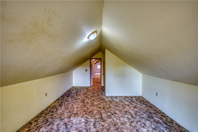 additional living space featuring lofted ceiling and carpet flooring