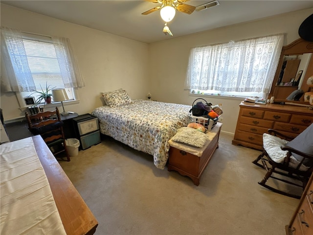 bedroom with multiple windows, light colored carpet, and ceiling fan