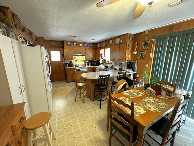 dining room featuring wood walls and ceiling fan