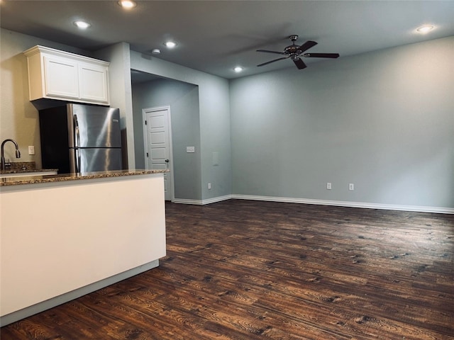 kitchen featuring white cabinetry, dark stone countertops, stainless steel fridge, ceiling fan, and dark wood-type flooring