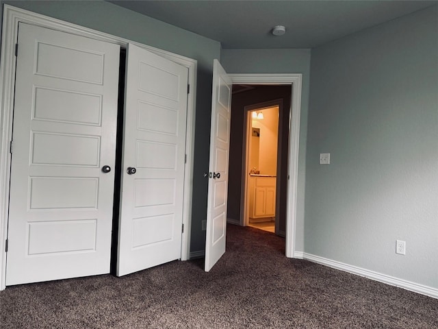 unfurnished bedroom with dark carpet and a closet