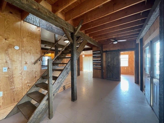 basement featuring wooden walls and ceiling fan