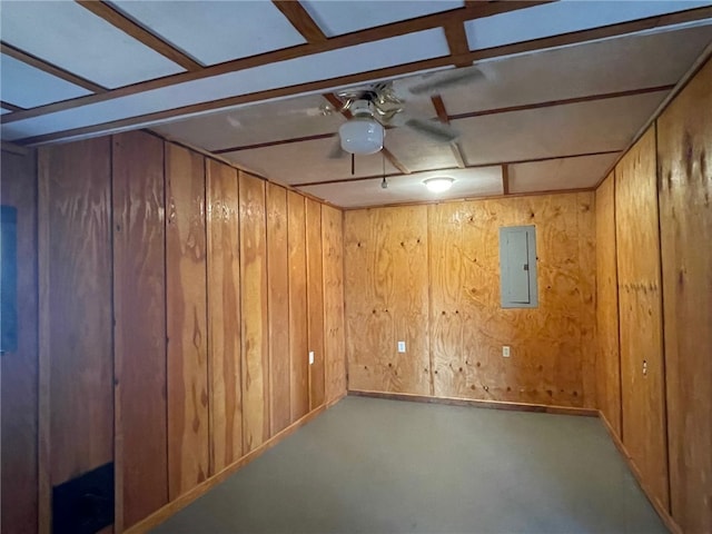 basement featuring wood walls, ceiling fan, and electric panel