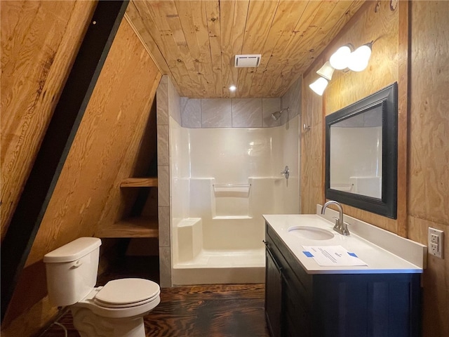 bathroom featuring toilet, wood ceiling, wooden walls, vanity, and a shower