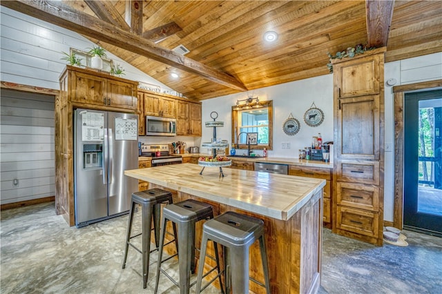 kitchen with stainless steel appliances, a kitchen breakfast bar, a kitchen island, wood counters, and lofted ceiling with beams