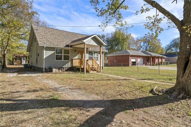 view of front of property featuring a shingled roof, dirt driveway, fence, cooling unit, and a front lawn