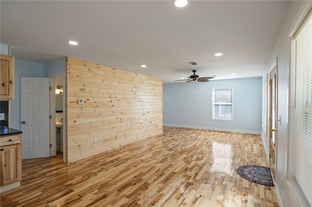 interior space with light wood-type flooring, visible vents, wood walls, and recessed lighting