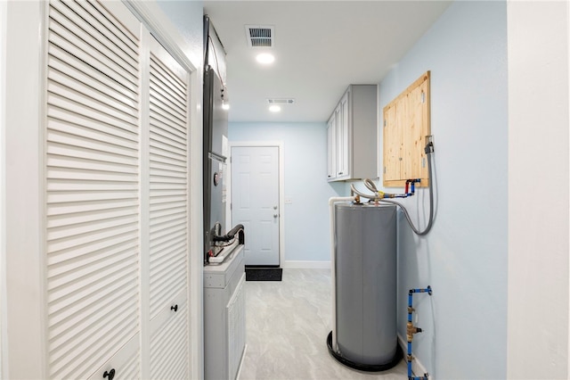 laundry area with gas water heater, visible vents, cabinet space, and baseboards