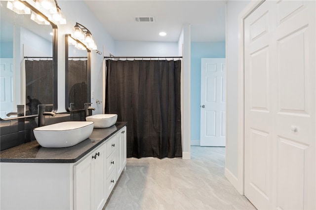 full bathroom featuring marble finish floor, double vanity, a sink, and visible vents