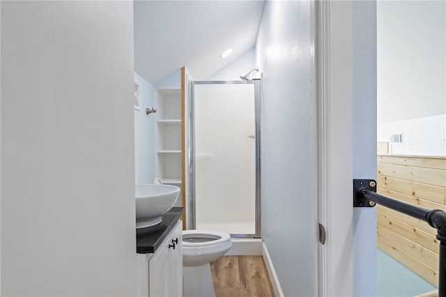 full bathroom featuring toilet, wood finished floors, vanity, vaulted ceiling, and a stall shower