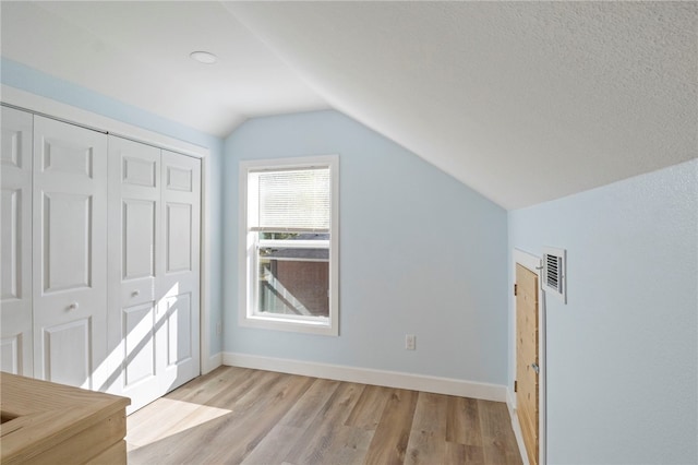 additional living space with lofted ceiling, light wood finished floors, baseboards, and visible vents