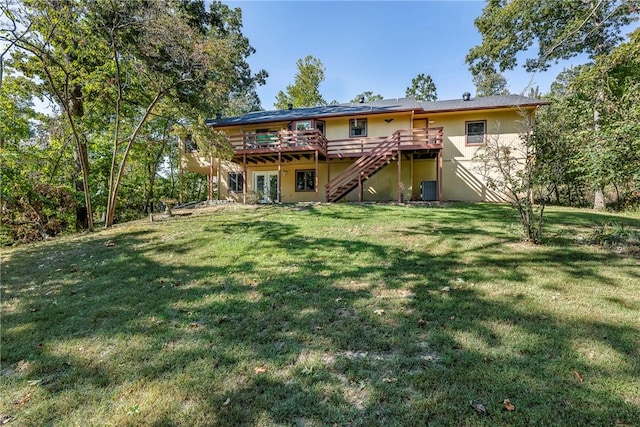 rear view of property with a deck, stairway, a yard, and stucco siding