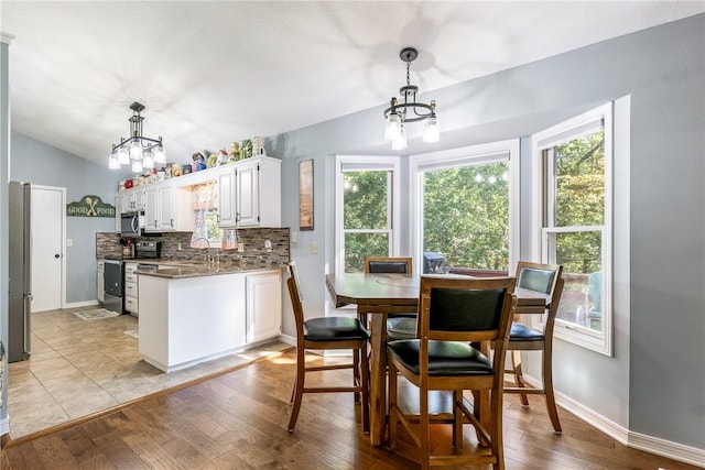 kitchen with a chandelier, plenty of natural light, appliances with stainless steel finishes, and lofted ceiling