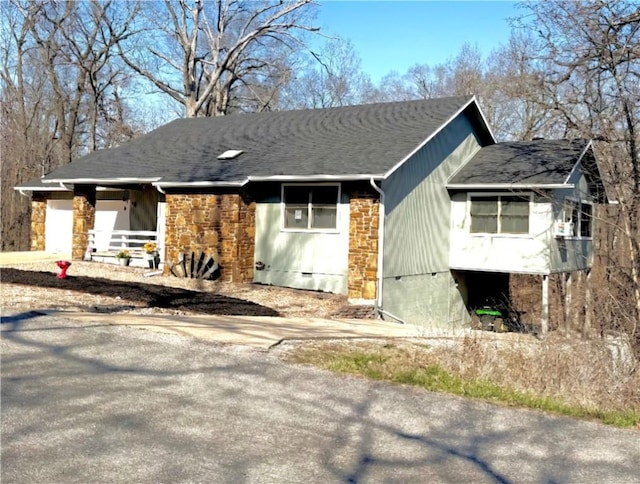 view of home's exterior with crawl space, stone siding, and roof with shingles