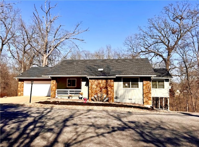 ranch-style house with stone siding, a porch, an attached garage, and driveway