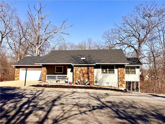 ranch-style home with driveway, an attached garage, covered porch, a shingled roof, and crawl space