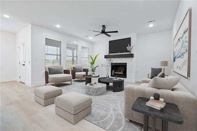 living room with ceiling fan, light hardwood / wood-style floors, and a fireplace