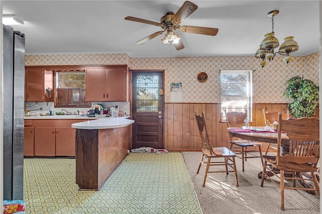 kitchen featuring pendant lighting, ceiling fan, sink, and wooden walls