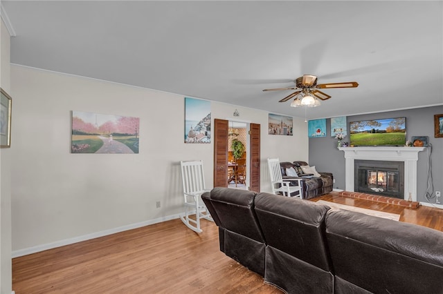 living room featuring a fireplace, light hardwood / wood-style floors, ceiling fan, and crown molding