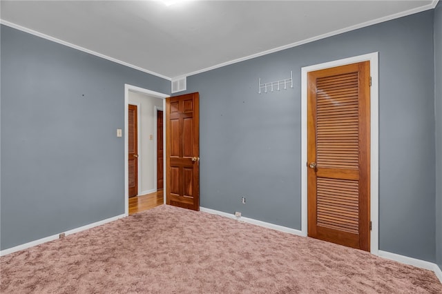 unfurnished bedroom with a closet, carpet floors, and ornamental molding