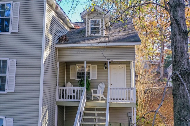 exterior space featuring stairway, a porch, and roof with shingles