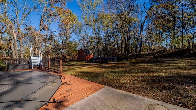 view of yard with a trampoline, a storage unit, and an outbuilding