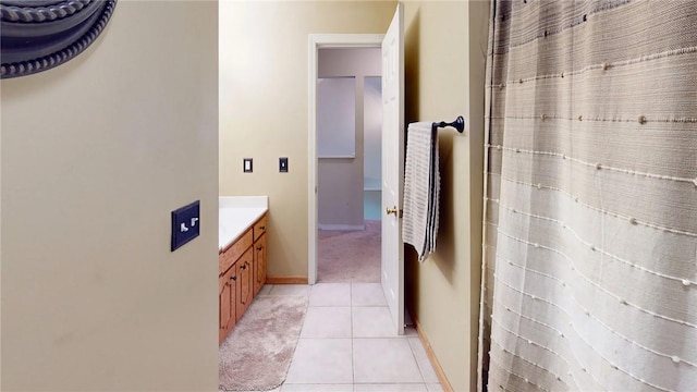 bathroom featuring curtained shower, tile patterned flooring, baseboards, and vanity