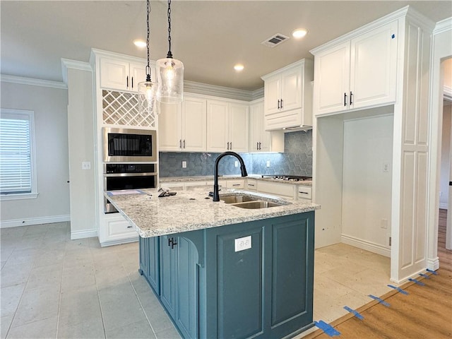 kitchen with sink, hanging light fixtures, stainless steel appliances, an island with sink, and white cabinets