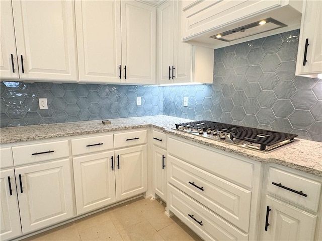 kitchen with backsplash, white cabinets, premium range hood, and stainless steel gas stovetop