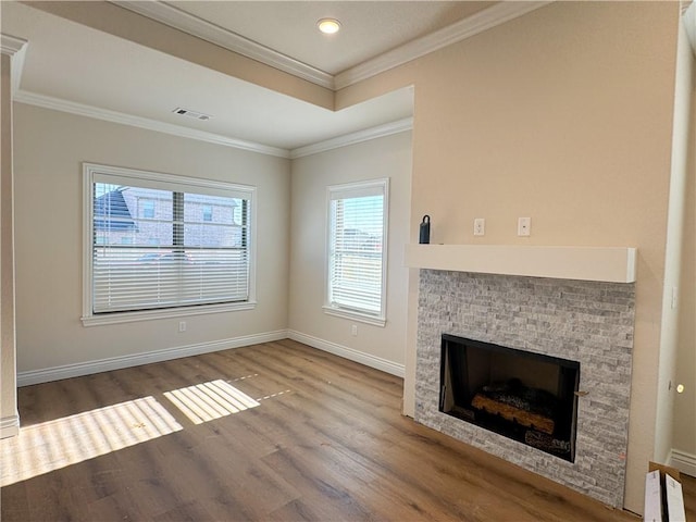 unfurnished living room with a stone fireplace, crown molding, and hardwood / wood-style floors