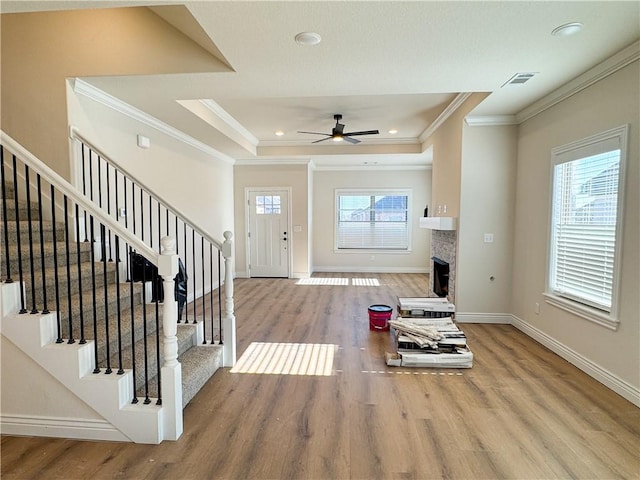 entrance foyer with ceiling fan, a healthy amount of sunlight, wood-type flooring, and ornamental molding