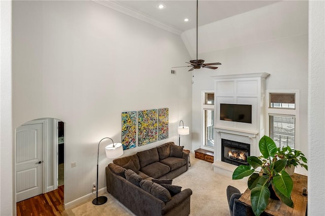 living room featuring ceiling fan, a towering ceiling, and ornamental molding