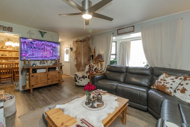 living room featuring wood-type flooring, ceiling fan, and crown molding