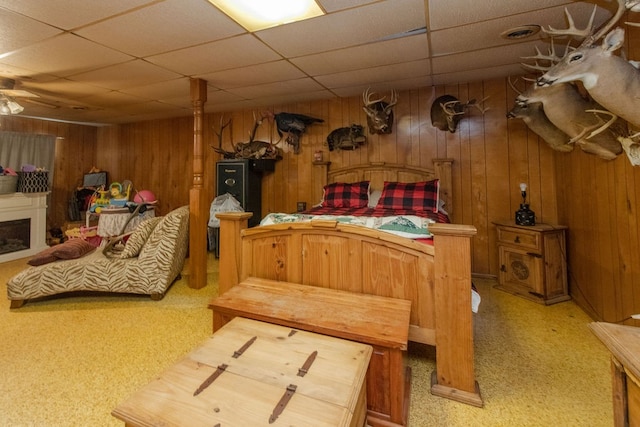 bedroom with a paneled ceiling, carpet, and wooden walls