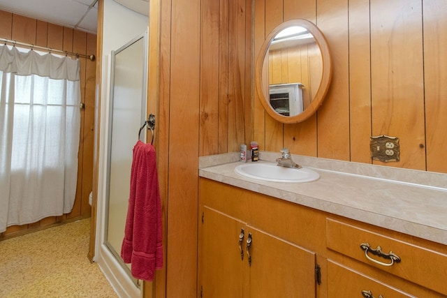 bathroom featuring vanity, wood walls, and a shower with door