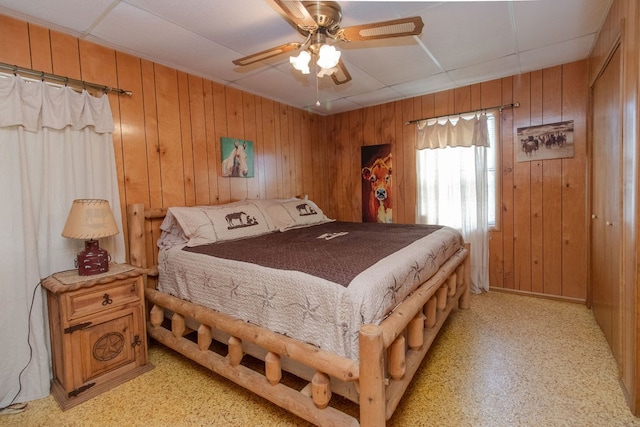 bedroom with ceiling fan and wooden walls