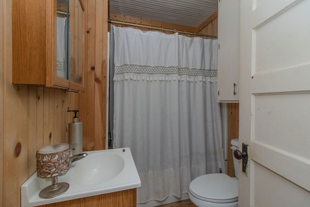 bathroom with curtained shower, wood walls, vanity, and toilet