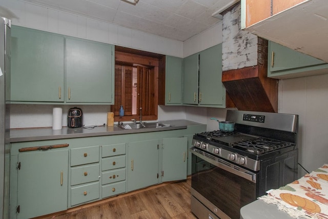 kitchen with gas stove, sink, green cabinetry, and light hardwood / wood-style flooring