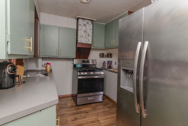 kitchen with hardwood / wood-style flooring, green cabinets, crown molding, and appliances with stainless steel finishes