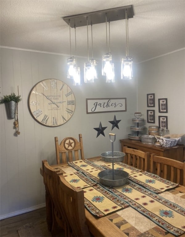 dining room featuring a textured ceiling, dark hardwood / wood-style flooring, crown molding, and wood walls