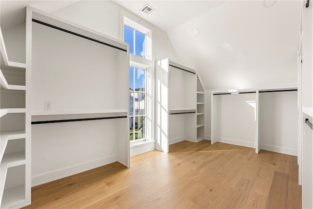 spacious closet featuring light wood-type flooring and lofted ceiling