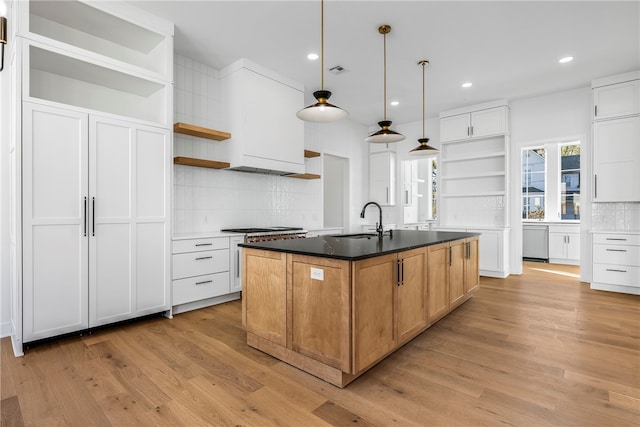 kitchen with white cabinetry, a kitchen island with sink, and light wood-type flooring