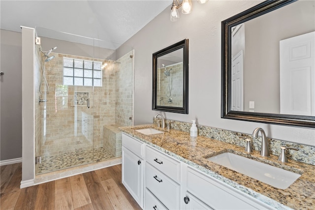 bathroom featuring hardwood / wood-style floors, vanity, a shower with door, and vaulted ceiling