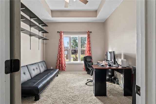 carpeted office featuring ceiling fan and a tray ceiling