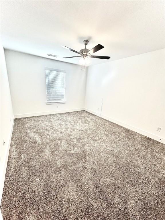 carpeted empty room featuring a ceiling fan, visible vents, and baseboards