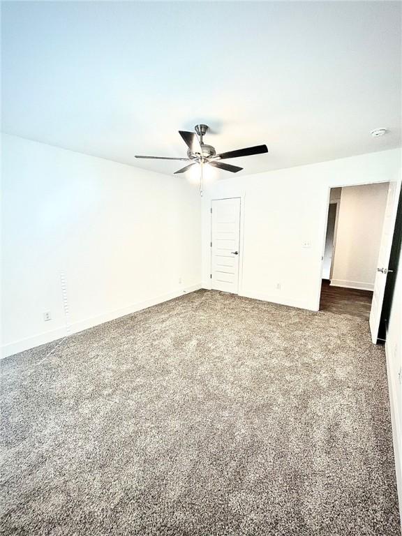 unfurnished room featuring ceiling fan and dark carpet