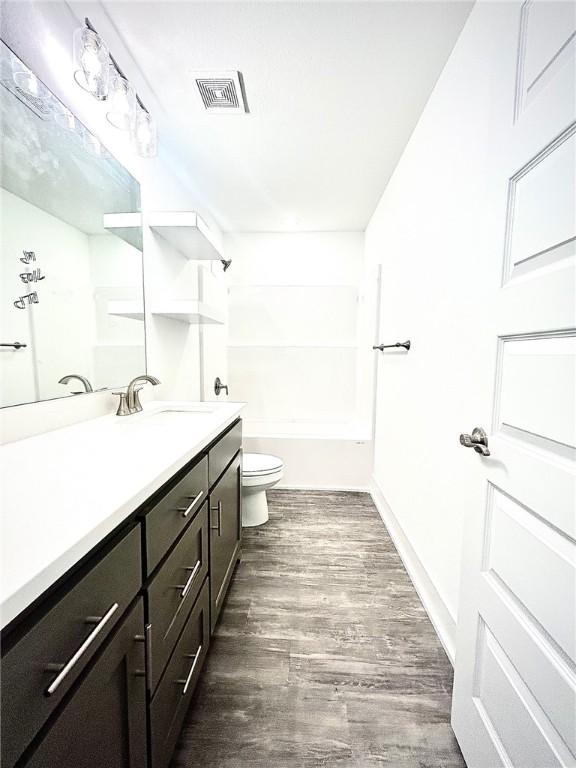 bathroom featuring shower / tub combination, toilet, wood finished floors, vanity, and visible vents