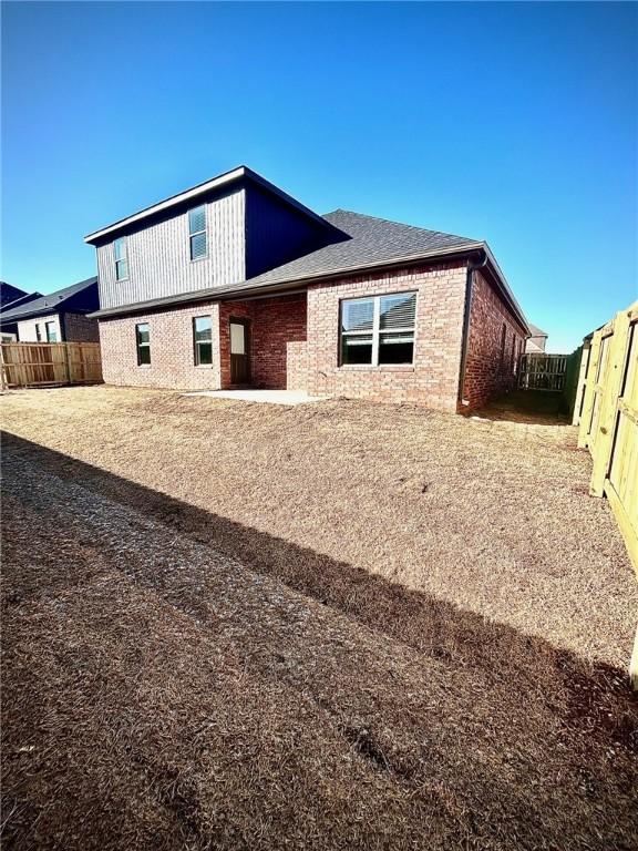 rear view of house with brick siding and a fenced backyard