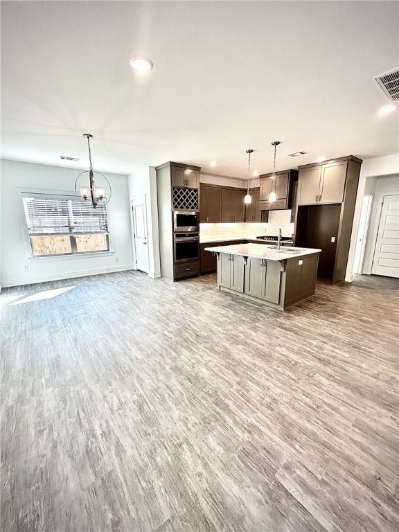 kitchen featuring light countertops, visible vents, open floor plan, wood finished floors, and oven